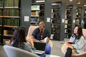 Three students are seated in a group in the library