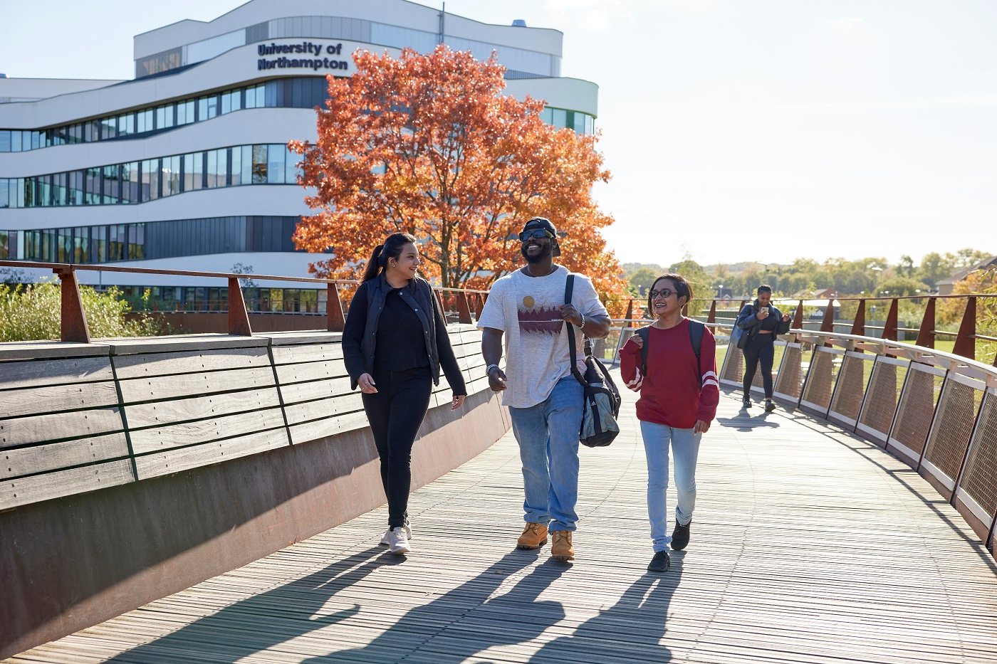 Three students walking over a bridge from Waterside campus