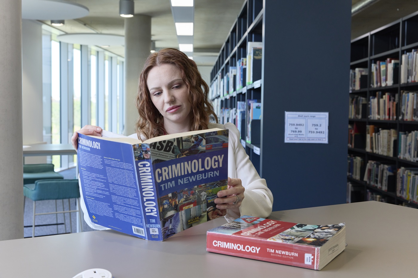 A student reads a Criminology textbook in the library