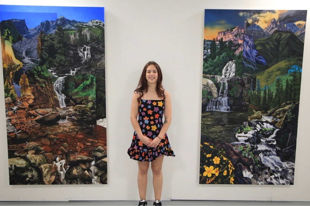 Ruby Fellows standing next to her paintings on the wall.