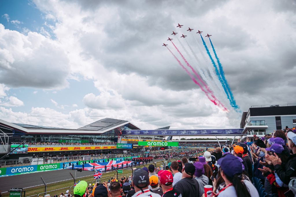 The Red Arrow trailing red, white and blue smoke as the fly over the starting grid at the British F1 Grand Prix.