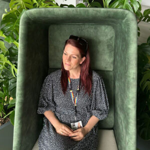 Hollie Darby, Sustainable Travel Advisor sitting in a green chair surrounded by green leaves