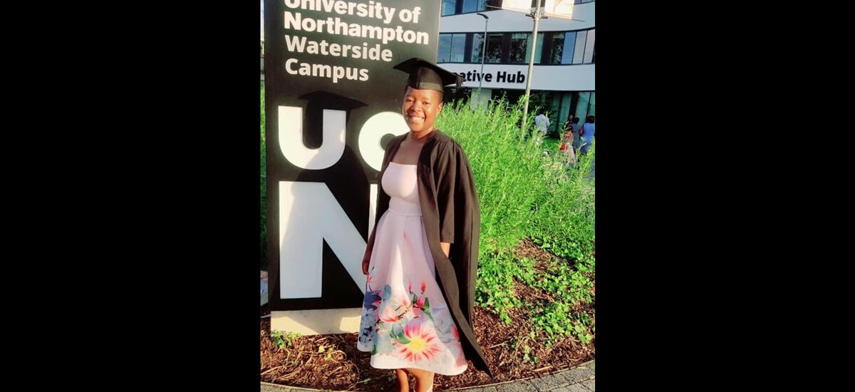 Primrose Sumasumo, Public Health MSc graduate on campus in graduation gown and cap