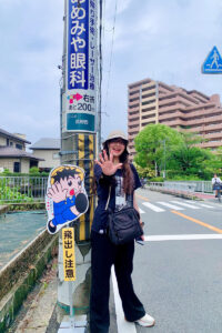Student Van Anh Nguyen in Japan, posing with a signs and stickers on the street in japanese.