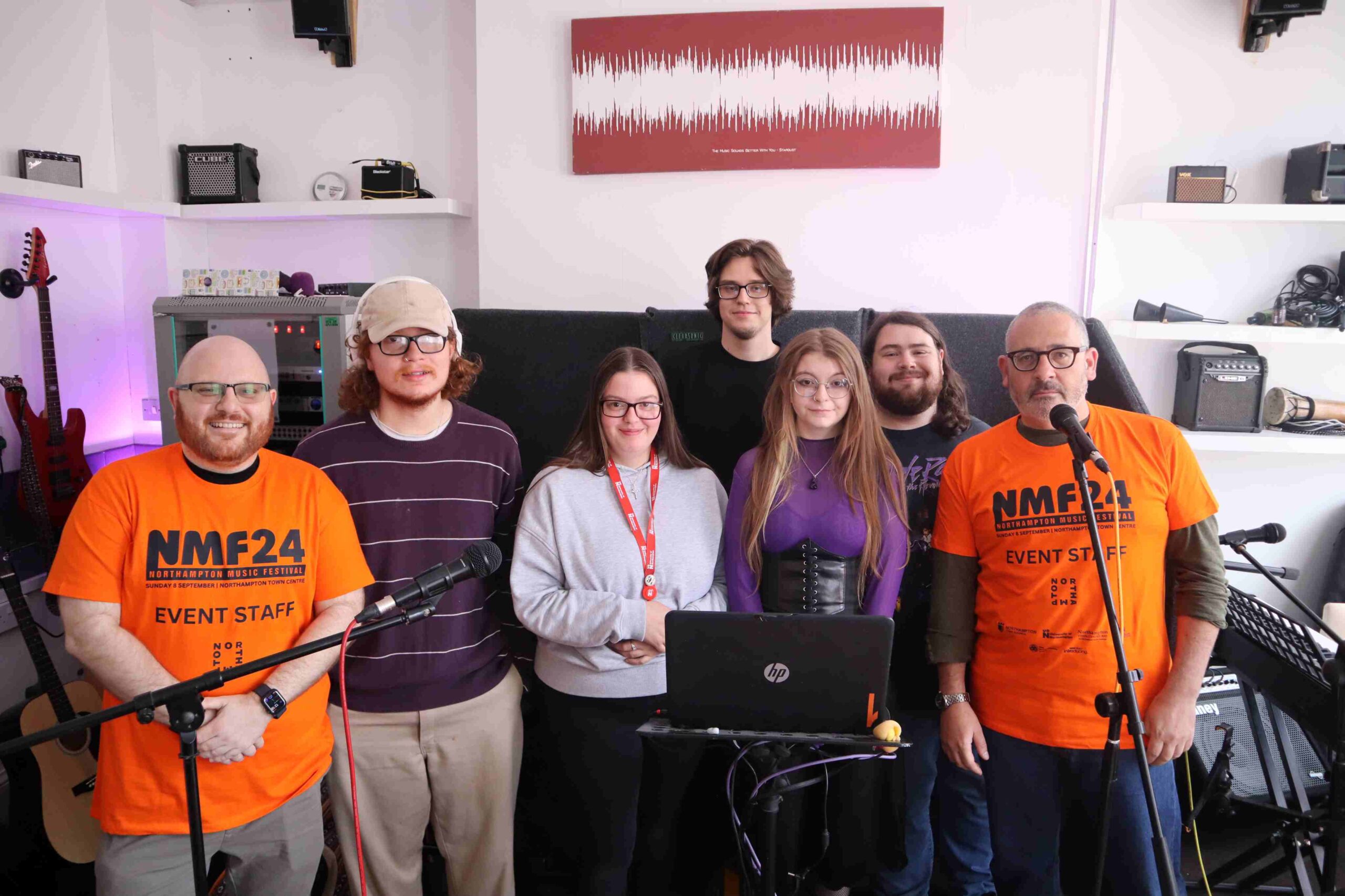 Academics and performers stand next to microphones in group photo.