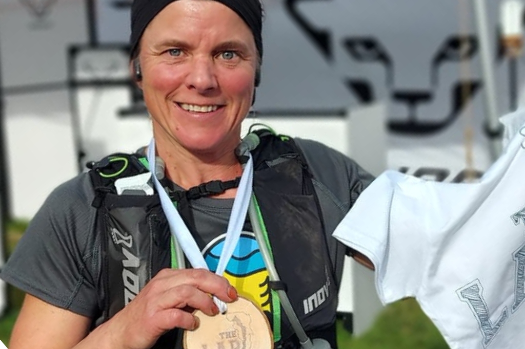 Lynne smiles at camera and holds up winning medal.