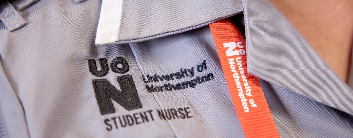 Close-up of a University of Northampton student nurse uniform with embroidered text and a lanyard.