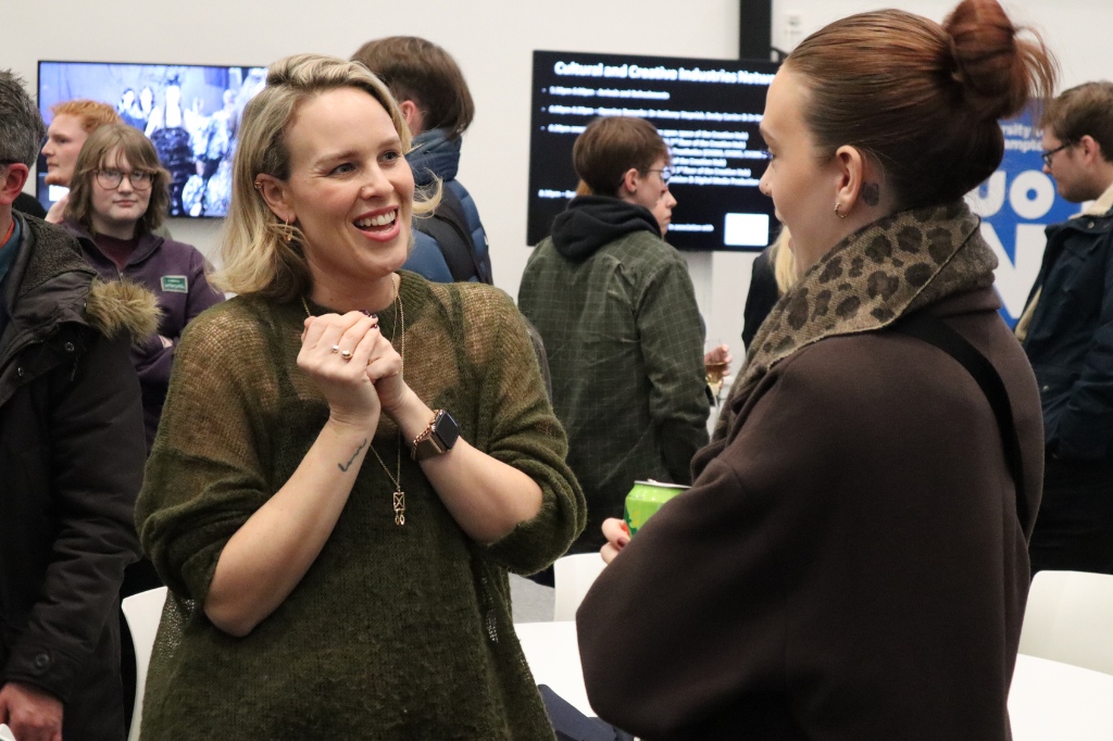 Jenny smiles at networking attendee in conversation.