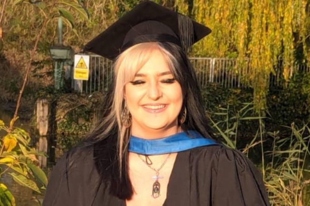 Ellie Abrahart smiles at camera in graduate hat.