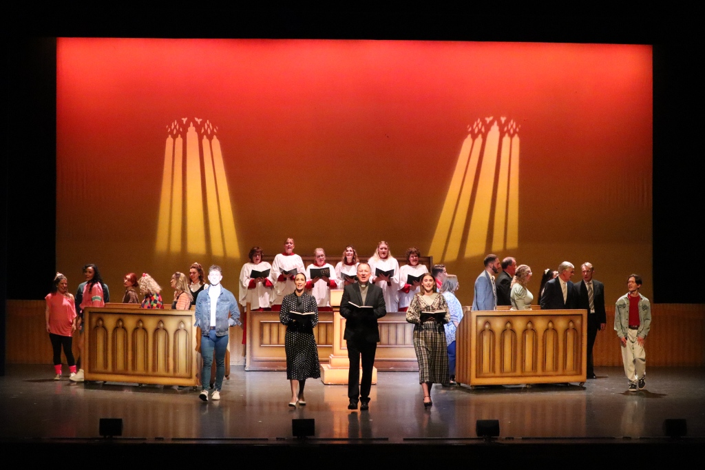 Actors sing and walk to the front of the stage for theatre production of Footloose.