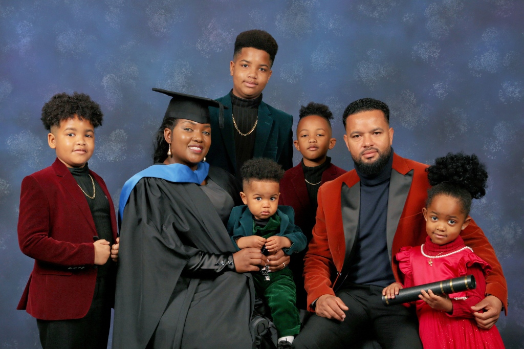 Mellonia Gray smiles in her graduation gown sat with her husband and five children.