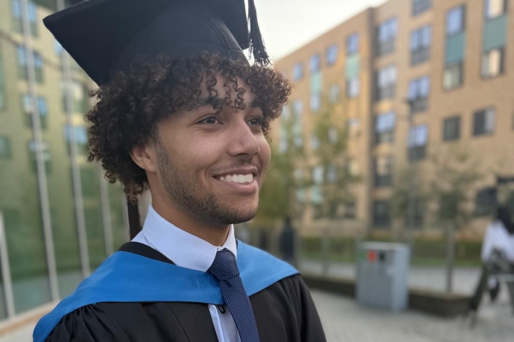 Jayden Lawrence smiles at camera in graduate hat.