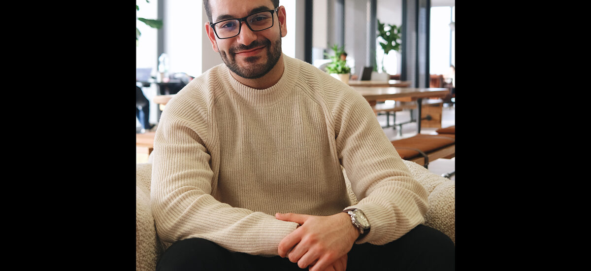 Ali Youssef, sitting in a modern office posing for the camera. The photo is professionally taken.