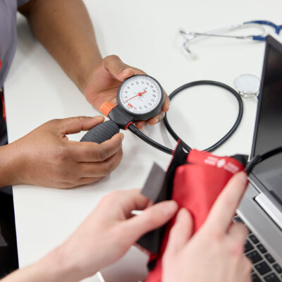 Button which shows a close up of an ultra sound scan being done to an ankle in the Podiatry Clinic. Only the hand of the podiatrist and the foot of the patient is seen.